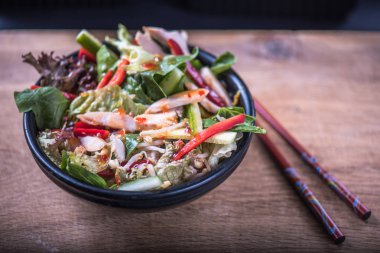 Kase yemek çubukları ile ahşap tabloda soslu taze sebze salatası