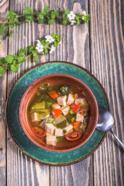 Ahşap yüzey üzerinde kase sebze çorbası tavuk ile hizmet