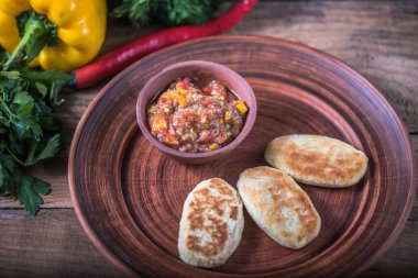 Kızarmış börek ve ahşap masa üzerinde kahverengi tabakta sebze güveç