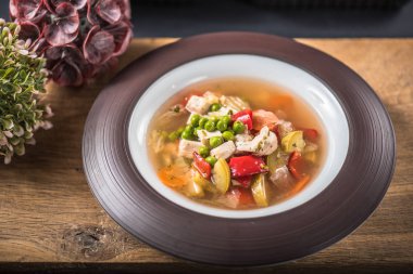 Ahşap yüzey üzerinde kase sebze çorbası tavuk ile hizmet