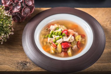 Ahşap yüzey üzerinde kase sebze çorbası tavuk ile hizmet