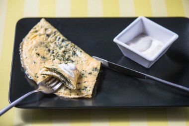 Sarı çizgili arka plan üzerinde soslu tabakta otlar ile ev yapımı omlet