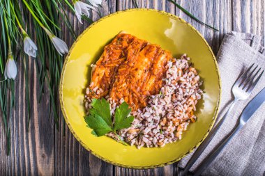 Ahşap masa üzerinde sarı plaka üzerinde pirinç ve Fırında Balık servis