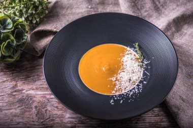 peynir ve ahşap masa üzerinde bitki ile süslenmiş krem balkabağı çorbası bölümünü