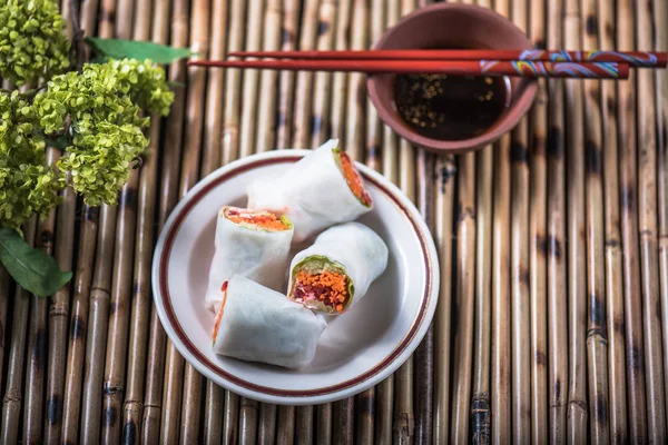 Japanese vegetable spring rolls on plate on bamboo napkin with soy sauce