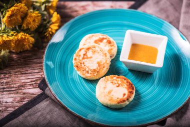 Çiçekli tahta masada mavi plaka üzerinde kızarmış peynir börek