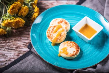 Çiçekli tahta masada mavi plaka üzerinde kızarmış peynir börek