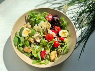 çiçekli beyaz yüzeyinde kasede yumurta ile deniz ürünleri salatası