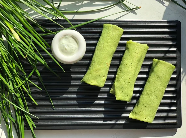 Vegetable green pancakes with dip on board on white background
