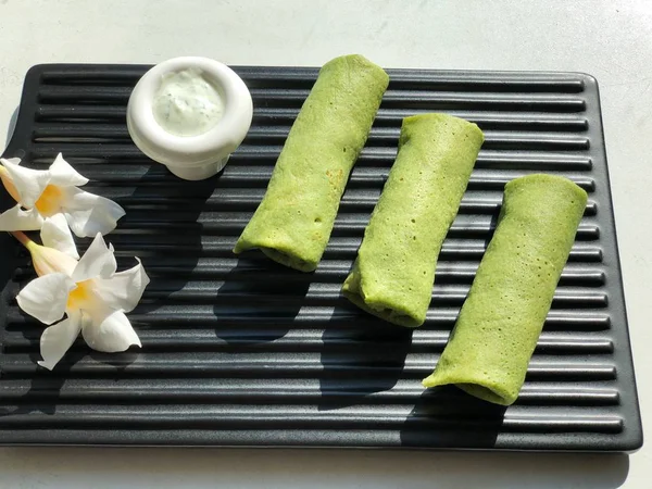 Vegetable green pancakes with dip on board on white background