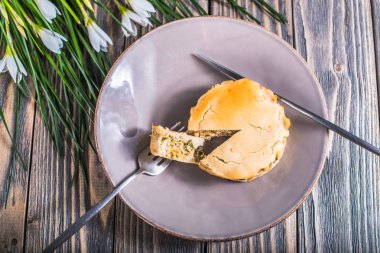 Menekşe plaka ve ahşap masaya güzel bahar çiçek et ve sebze ile lezzetli pişmiş pasta, çatal bıçakla Üstten Görünüm