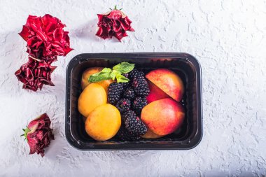 Kayısı, şeftali ve böğürtlen çiçekleri beyaz zemin üzerine plastik kap içinde taze parçaları