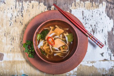 Berbat ahşap masada kase balık ve noodle ile Asya çorbası