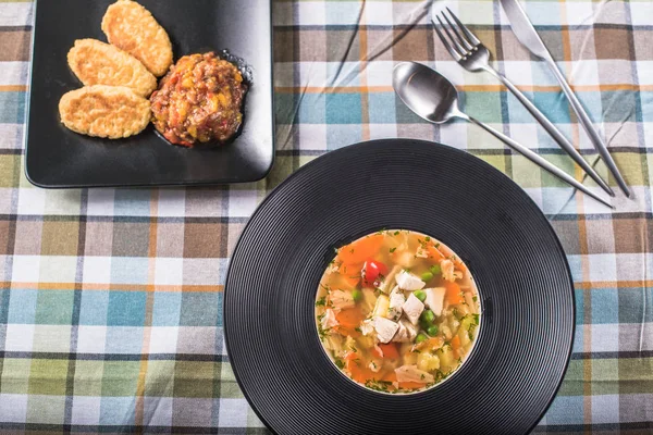 Homemade soup in plate on checkered tablecloth