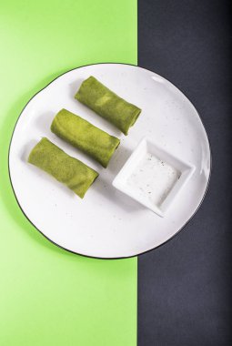 Dalış yeşil ve gri yüzeyi beyaz tabakta sebze yeşil krep