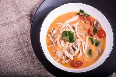 Gri masa örtüsü üzerinde kase tavuk ve mantar ile domates çorbası