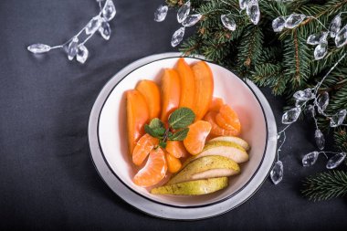 Trabzon hurması, elma ve arka plan üzerinde Noel dekorasyonu ile plaka üzerinde mandarin taze parçaları