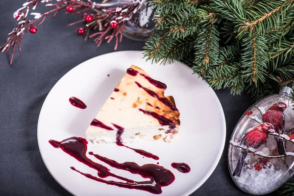 Stück Käsekuchen Mit Marmelade Auf Teller Auf Hintergrund Der Weihnachtsdekoration — Stockfoto