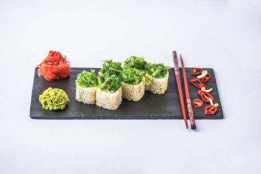 Kayrak beyaz zemin üzerine alınarak deniz yosunu ile süslenmiş Japon suşi roll
