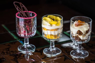 Kahverengi fayans yüzeyinde gözlük farklı tatlı krem tatlılar