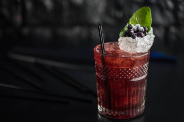 Yaprak ve koyu arka plan üzerinde yaban mersini taze kokteyl cam süslenmiş