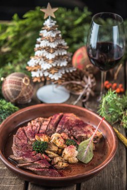 kase ve Noel dekorasyonu ile masada kırmızı şarap soslu kızarmış et