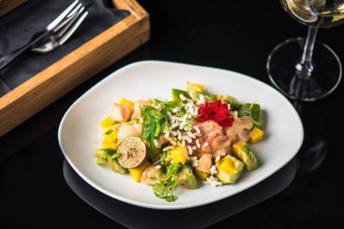 İncelik sebze salatası kadeh beyaz şarap ile siyah arka plan üzerine tabakta servis