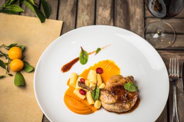 Ahşap masa üzerinde beyaz tabakta ördek bacak garnitür ile servis