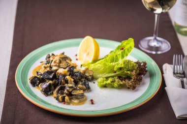 Beyaz şarap cam ile masa örtüsü üzerinde tabak limon ve salata ile deniz ürünleri çanak