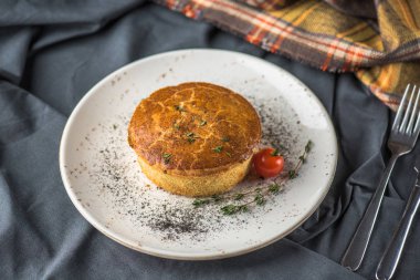 Ev yapımı tuzlu pasta plaka üzerinde gri masa örtüsü domatese ile pişmiş