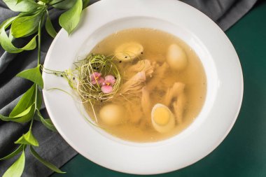 Tavuk suyu ile dekoratif yuva koyu arka plan üzerinde beyaz plaka servis