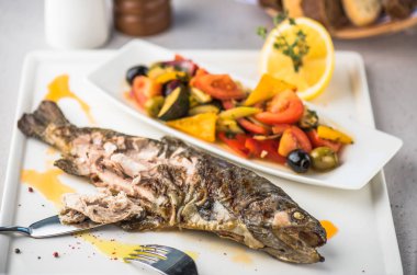 Izgara balık tabakta taze sebze salatası ve limon ile