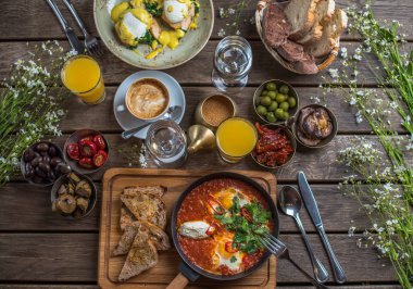 shakshuka, zeytin, biber, domates, ekmek, meyve suyu ve kahve rustik ahşap tablo ile kahvaltı