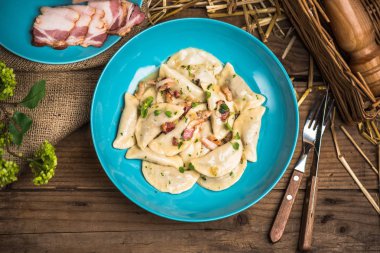 Ahşap masa üzerinde mavi plaka üzerinde Kurutulmuş domuz pastırması ile servis haşlanmış Mantı