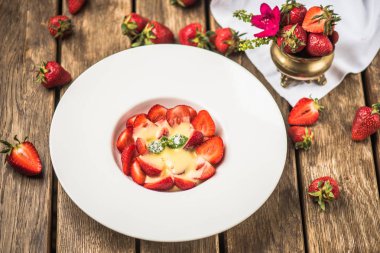 Beyaz ahşap masa tabakta servis kremalı çilekli tatlı