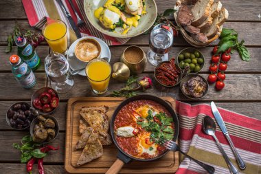 shakshuka, zeytin, biber, domates, ekmek, meyve suyu ve kahve rustik ahşap tablo ile kahvaltı