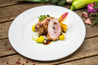 Beyaz ahşap masa üzerinde sebzeli tabakta kavrulmuş domuz eti