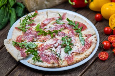 Roka ve ham ahşap masa üzerinde plaka üzerinde İtalyan pizza