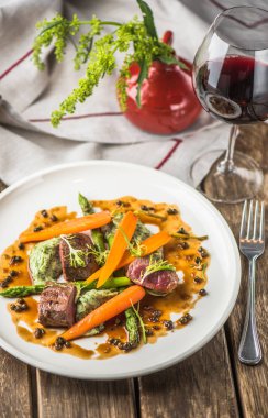 Havuç ile sığır eti ve ahşap masa üzerinde sunulan beyaz tabakta sos