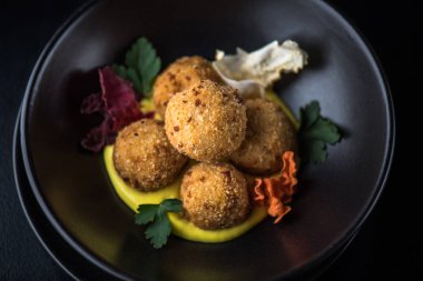 Derin kızarmış peynir topu yığılmış siyah kase sos ile servis