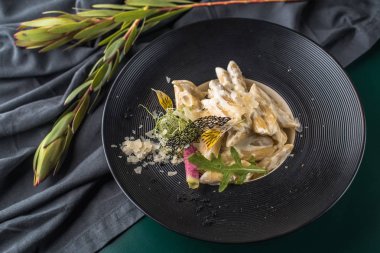 Krema soslu makarna çeşitleri siyah plaka üzerinde karanlık masa örtüsü yılları arasında görev yapmıştır