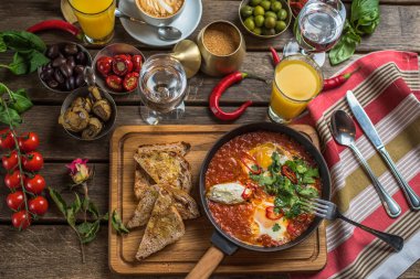 shakshuka, zeytin, biber, domates, ekmek, meyve suyu ve kahve rustik ahşap tablo ile kahvaltı