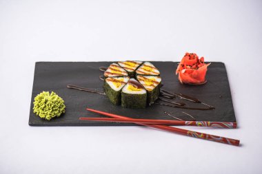 zencefil, wasabi, soya sosu ve gri arka plan üzerinde kayrak gemide yemek çubukları ile lezzetli üçgen suşi