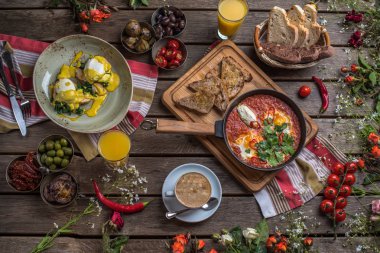 shakshuka, zeytin, biber, domates, ekmek, meyve suyu ve kahve rustik ahşap tablo ile kahvaltı