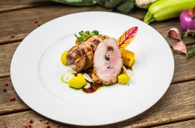 Beyaz ahşap masa üzerinde sebzeli tabakta kavrulmuş domuz eti