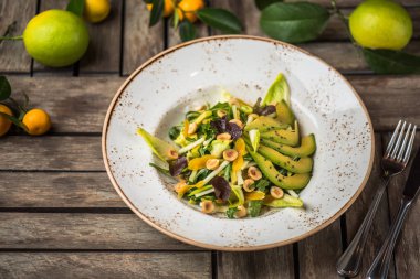 Taze salata avokado ve plaka üzerinde ahşap masa içinde fındık