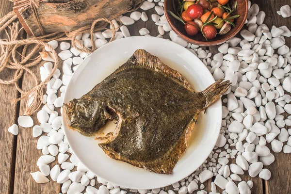 grilled sole fish on plate on wooden table with bowl of vegetables