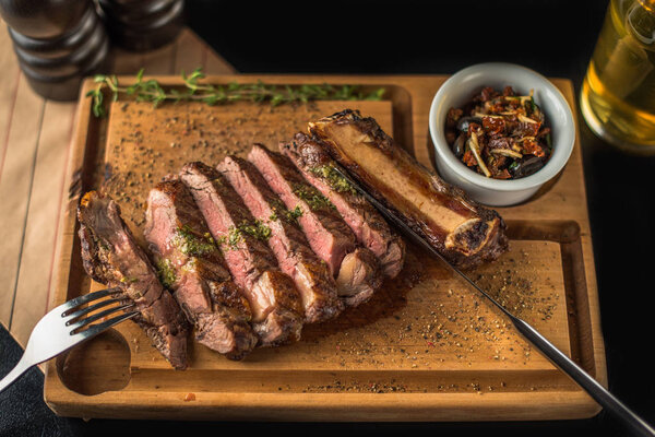 Sliced spiced grilled steak on wooden board with dried tomatoes