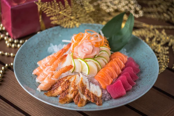 Fresh seafood sashimi on ice in plate on wooden table with christmas decor