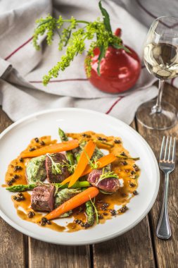 Havuç ile sığır eti ve ahşap masa üzerinde sunulan beyaz tabakta sos